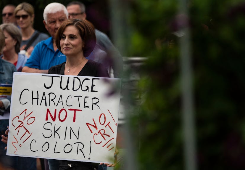 A woman holds up a sign during a rally against "critical race theory" (CRT) being taught in schools ...