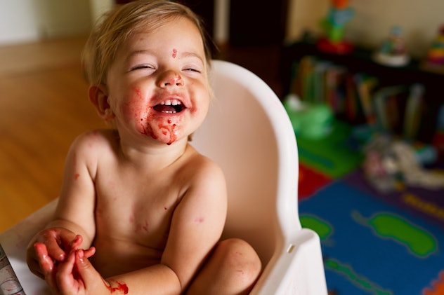 baby with his face messy from eating cherries