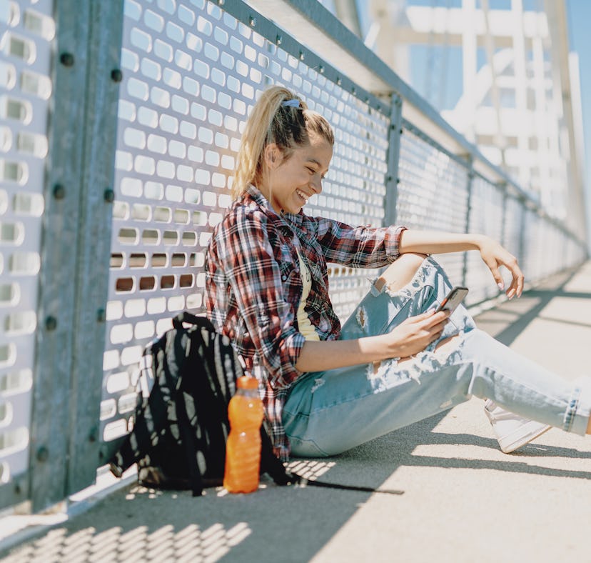A teenager in the city with backpack looks at some POV TikTok video ideas for back-to-school videos....