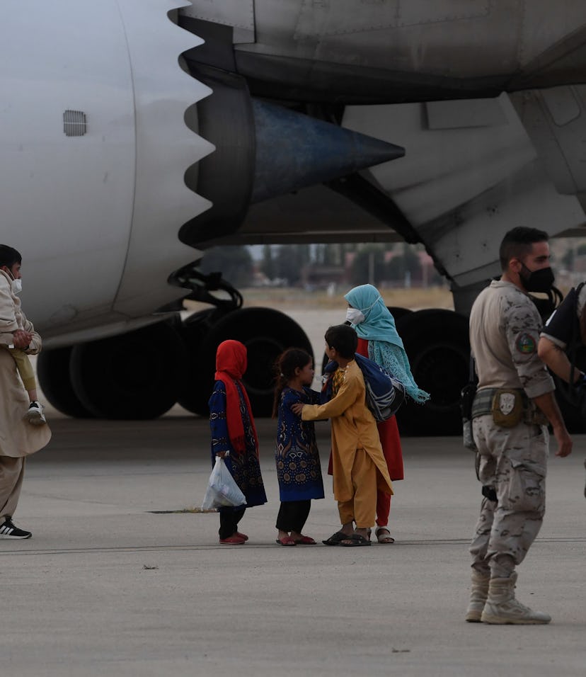 Military personnel stand on the tarmac as refugees disembark from an evacuation flight from Kabul, a...