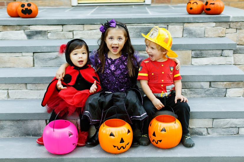 three kids in halloween costumes with pumpkin buckets