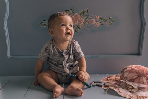 Baby smiling sitting next to a retro fashion hat
