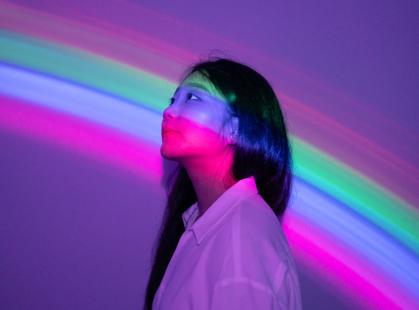 Young woman in rainbow neon lights during the September 2021 full moon in Pisces, which will affect ...