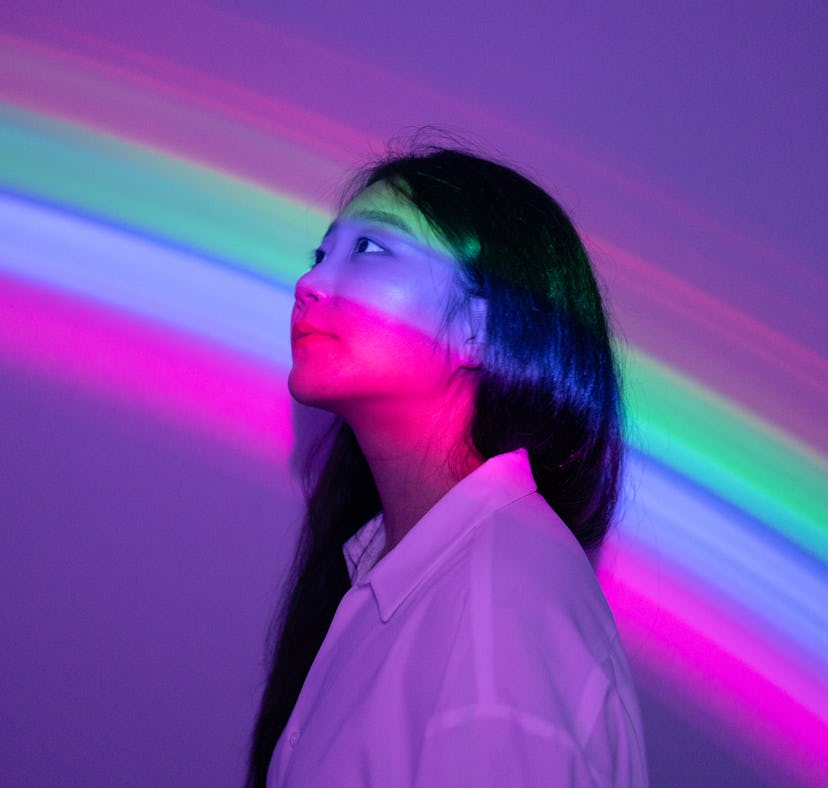 Young woman in rainbow neon lights during the September 2021 full moon in Pisces, which will affect ...