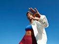 Portrait of active sportswoman wearing jacket with sports clothing against clear sky during sunny da...
