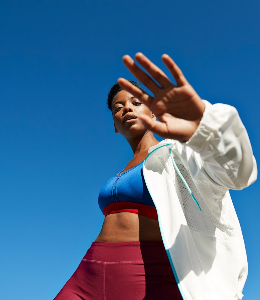 Portrait of active sportswoman wearing jacket with sports clothing against clear sky during sunny da...