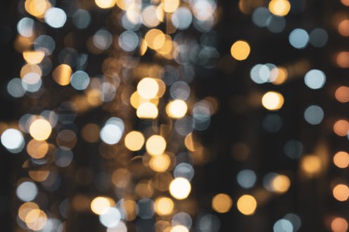 Christmas lights. Festive New Year blurred white, golden yellow, blue and black background. Beautifu...