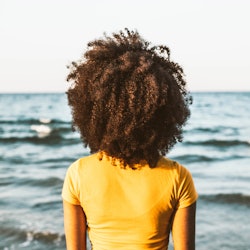 A woman looks out onto the ocean with her back to the camera. Here are 18 personality traits of peop...