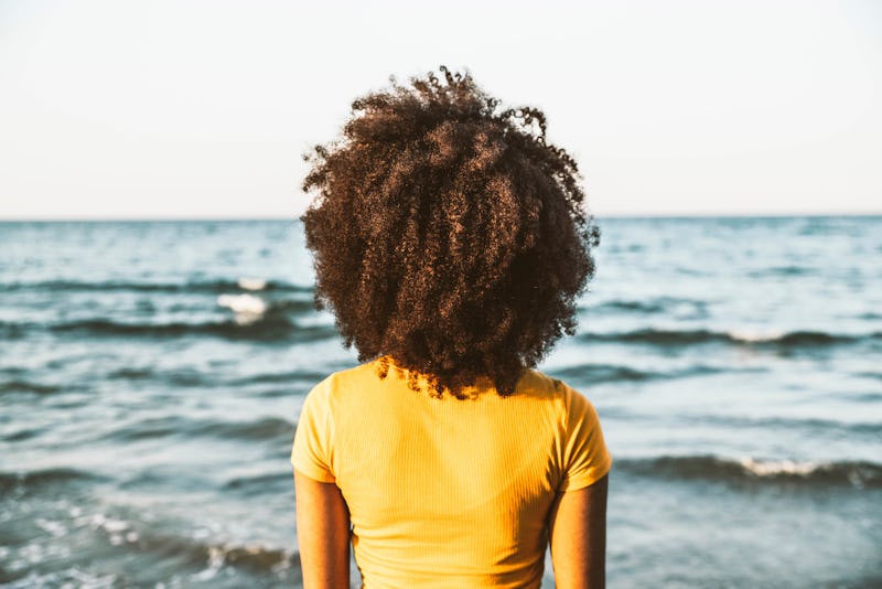 A woman looks out onto the ocean with her back to the camera. Here are 18 personality traits of peop...