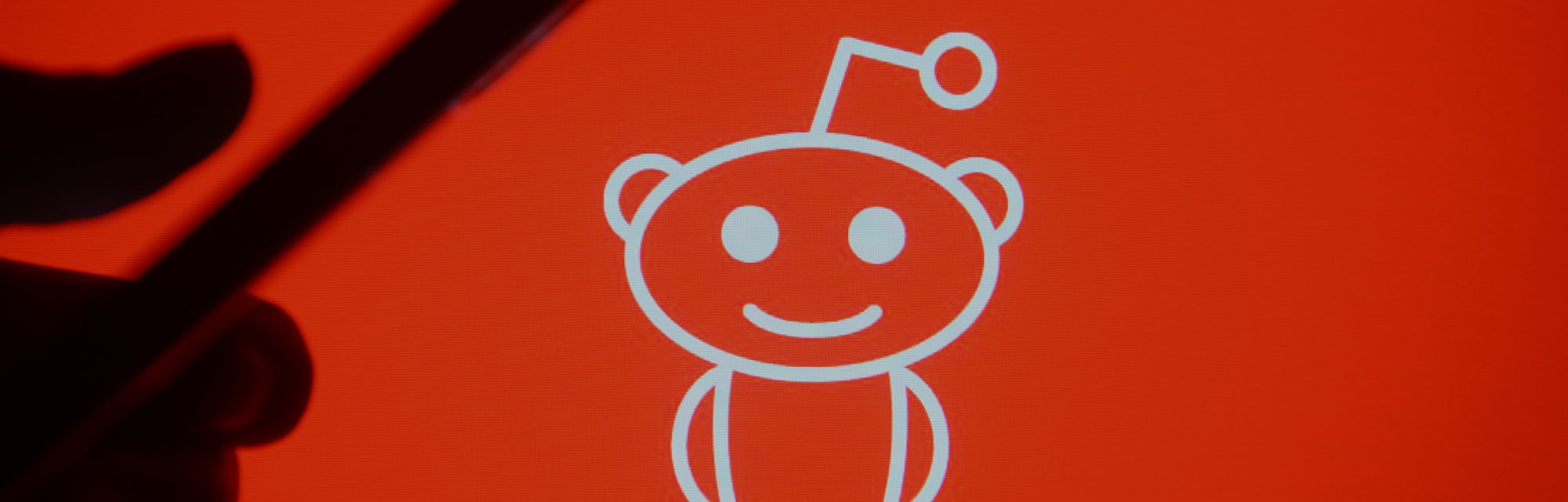 UKRAINE - 2021/03/07: In this photo illustration a silhouette hand holding a mobile phone with a Red...