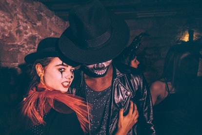 Young multi-ethnic couple in Halloween costumes and scary make-up having fun at night party