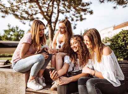 Sorority sisters in the same pledge class look at their phones and decide on group chat names. 