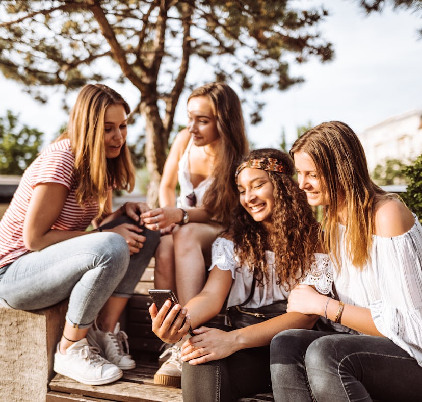 Sorority sisters in the same pledge class look at their phones and decide on group chat names.