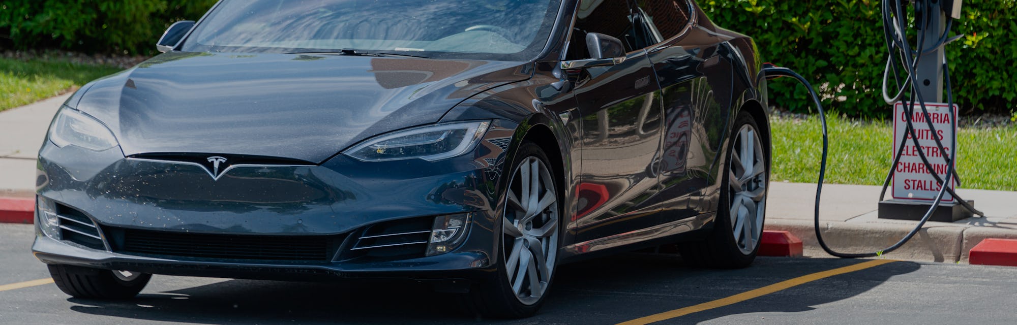 Tesla electric car being charged at a charging station located in the parking lot of a Cambria Suite...