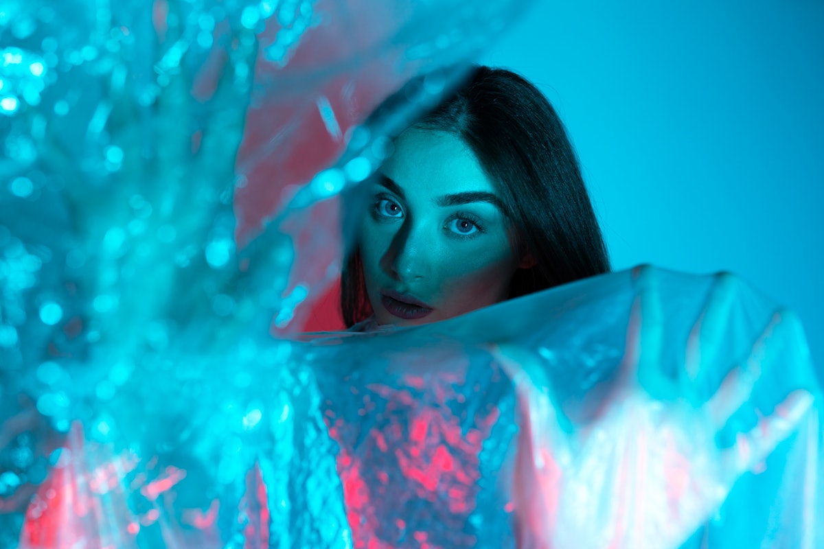 Mulher modelo de alta moda em azul neon colorido e luzes roxas posando em estúdio. Retrato o...