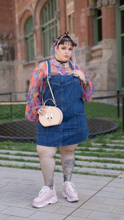 Plus-size influencer beautifully styles a pair of denim overalls as a dress with a long sleeve top, ...