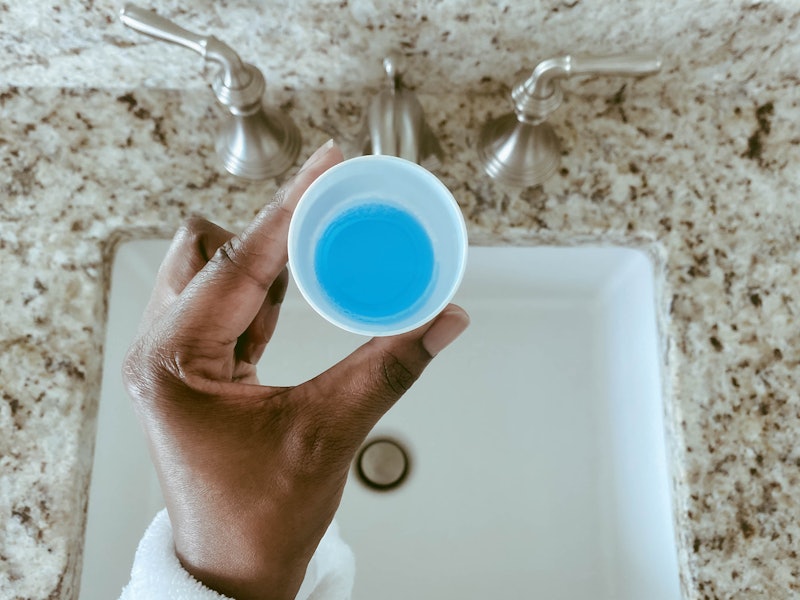 Close-up of woman's hand holding cup of mouthwash. Dentists explain the benefits of mouthwash.