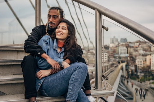 Two people, black man and white woman, young couple sitting on steps outdoors in city.