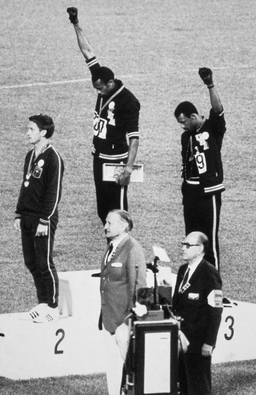 American sprinters Tommie Smith and John Carlos raise their fists and give the Black Power Salute at...