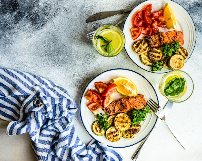 overhead image of two plates full of zucchini, tomato, and salmon