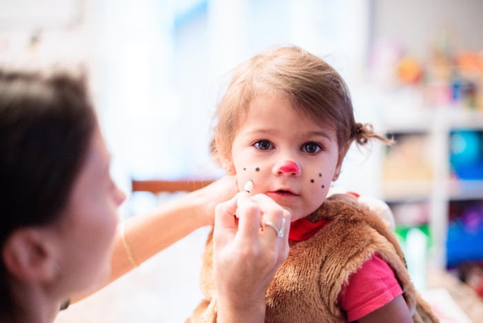 little girl in dog halloween costume getting makeup on her face
