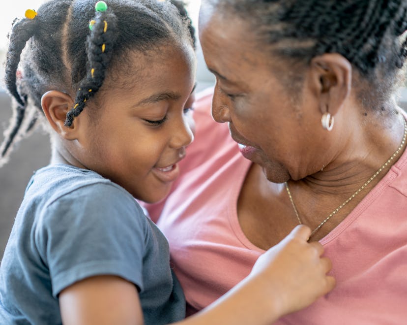 A girls smiles while sitting on the couch and hugging her grandmother, what to know about grandparen...