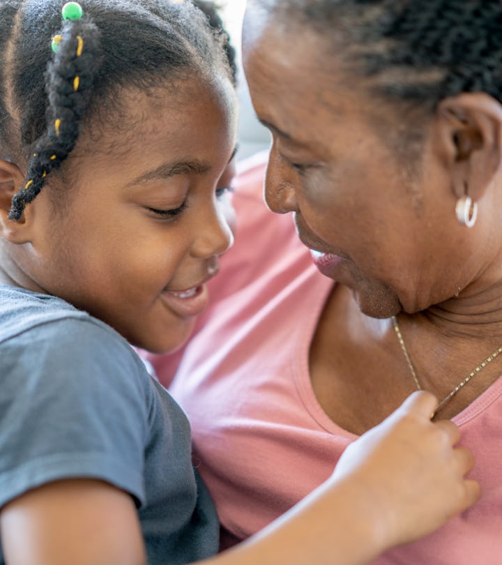 A girls smiles while sitting on the couch and hugging her grandmother, what to know about grandparen...