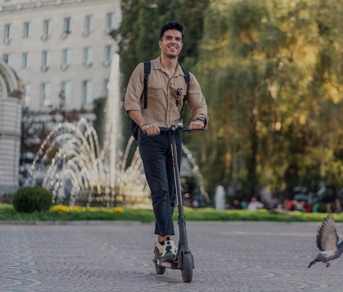 Young man riding electric scooter in the city center