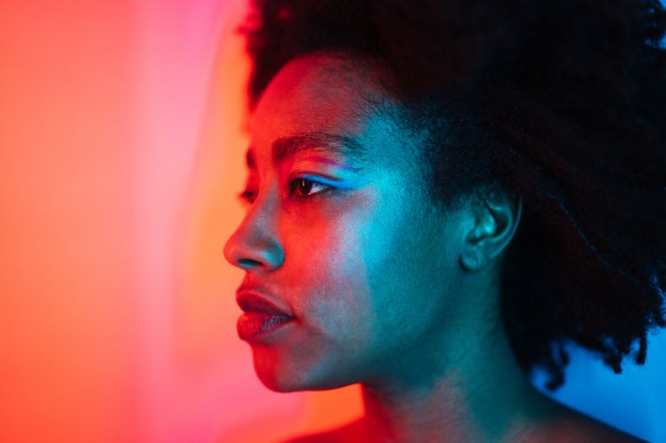 Portrait of a young edgy woman under neon lights; studio shot, isolated.