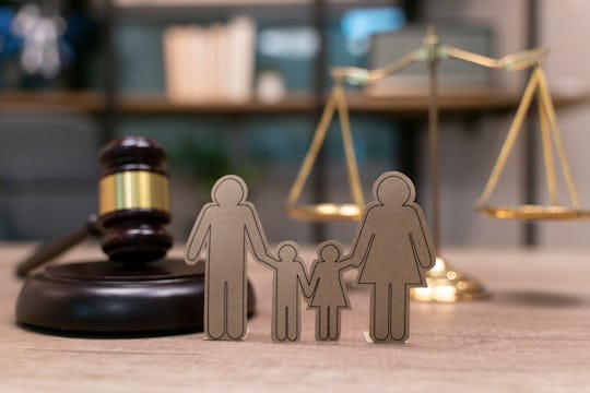 A paper cutout of a family of four is displayed near a judge's gavel and scales to represent family ...