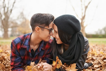 A happy couple lays in a leaf pile for their fall engagement photos, which they'll post to Instagram...