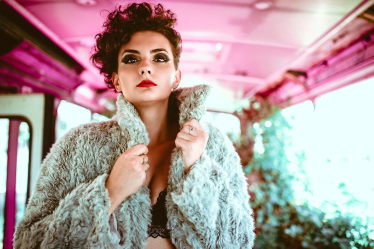 Sensual young sexy woman wearing just lingerie and fur coat in old bus.