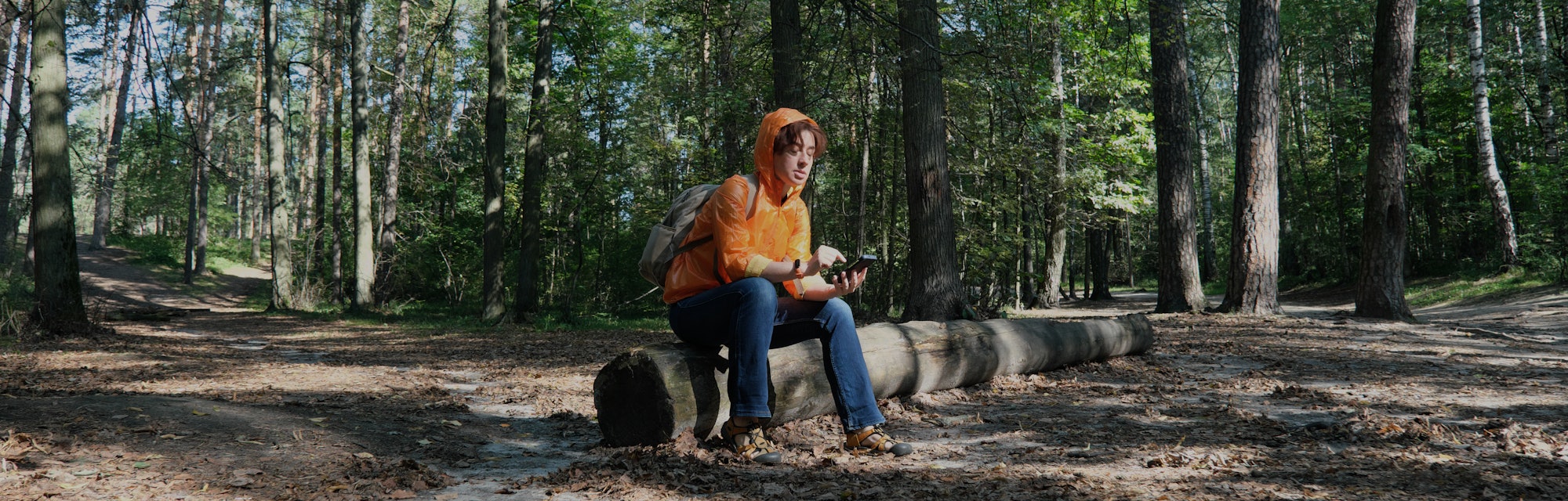 Mature woman hiking in forest is trying to get the direction using GPS in her smart phone