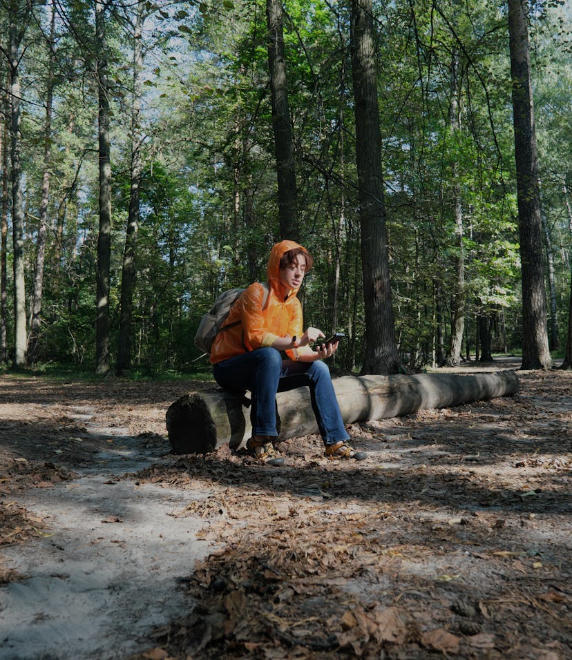 Mature woman hiking in forest is trying to get the direction using GPS in her smart phone