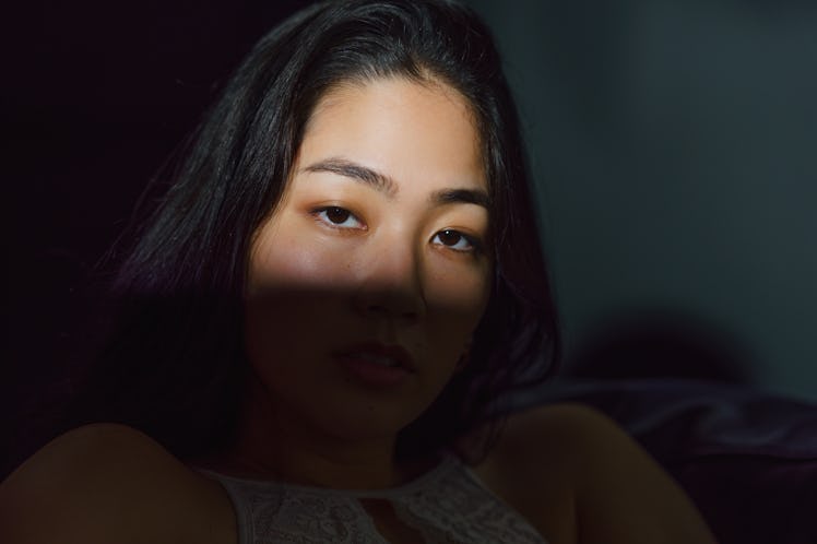 young woman face covered in shadow, reflecting on the grand cross in her birth chart