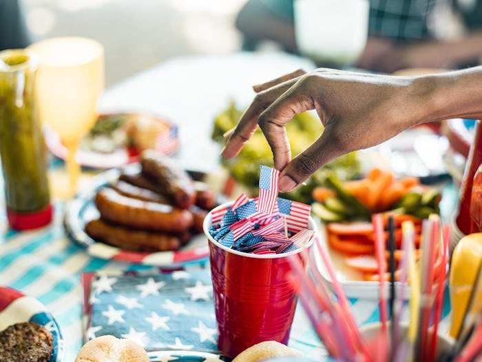 Hand of Black woman picking up a American flag stick from red solo cup on picnic table 