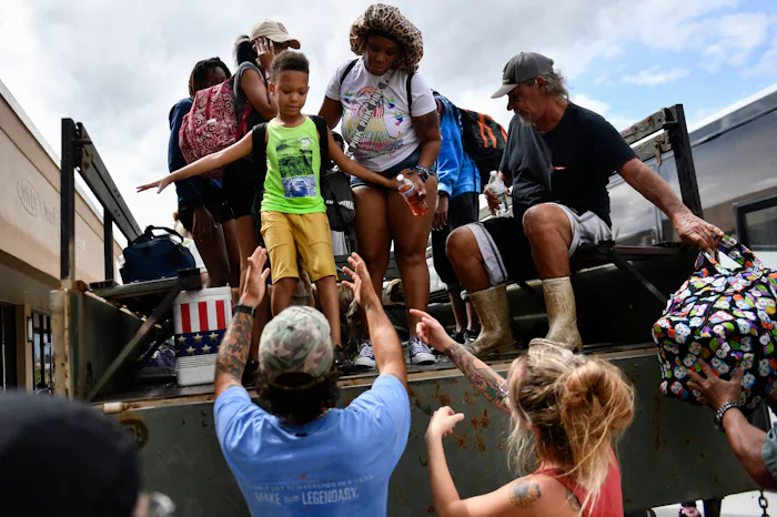 Volunteers Hunter Louque (L) of Saint Amant and Desiree Nye (R) help a child out of a high water tru...