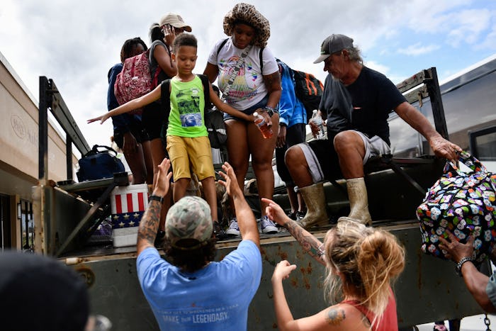 Volunteers Hunter Louque (L) of Saint Amant and Desiree Nye (R) help a child out of a high water tru...