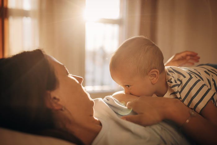 mother breastfeeding her baby boy son in bedroom at home.