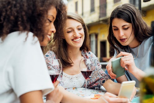 Three people look at the same phone over dinner. Figuring out how to name your group chats doesn't h...