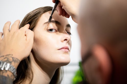 MILAN, ITALY - SEPTEMBER 27: A make up artist does the final touch  of gel eyebrow during the line u...