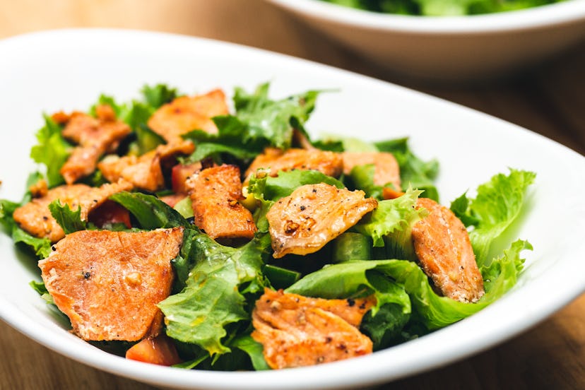 A white bowl of seared salmon fillet salad photography