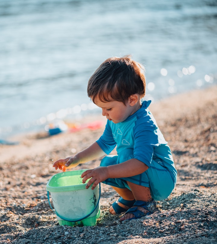 Baby Boy Plays With Toy Bucket in the Sea