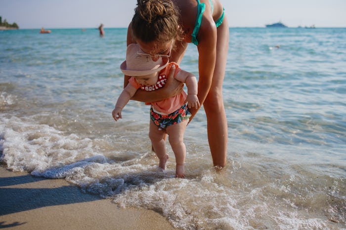 Mother holding her 6 months old baby at beach in water