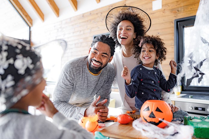 Happy African American family talking while having Halloween celebration at home.