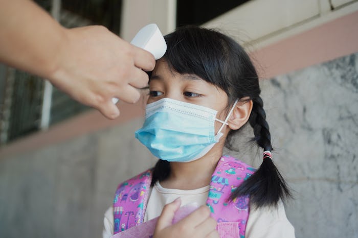 Temperature screening and medical check at school.Teacher with thermometer at preschool entrance che...
