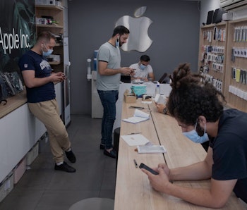 Iranian staff use their smartphones at an apple shop in northern Tehran on June 19, 2021. - Ultracon...
