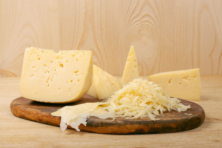 Pieces of cheese and grated cheese on the wooden board. Dutch cheese texture. Concept of healthy and...
