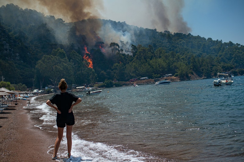 A woman watches the forest burn from a beach in Mugla, a Marmaris' district, as Turkey struggles aga...