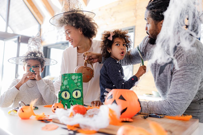 Happy black parents and their kids enjoying during Halloween celebration at home, halloween knock kn...